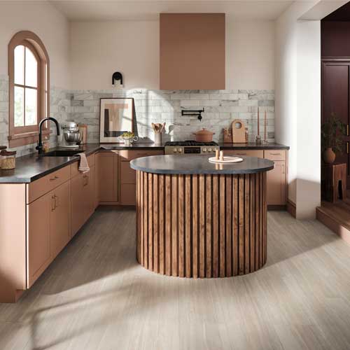 traditional kitchen with stone tile backsplash, wood look floors, clay colored cabinets and round island